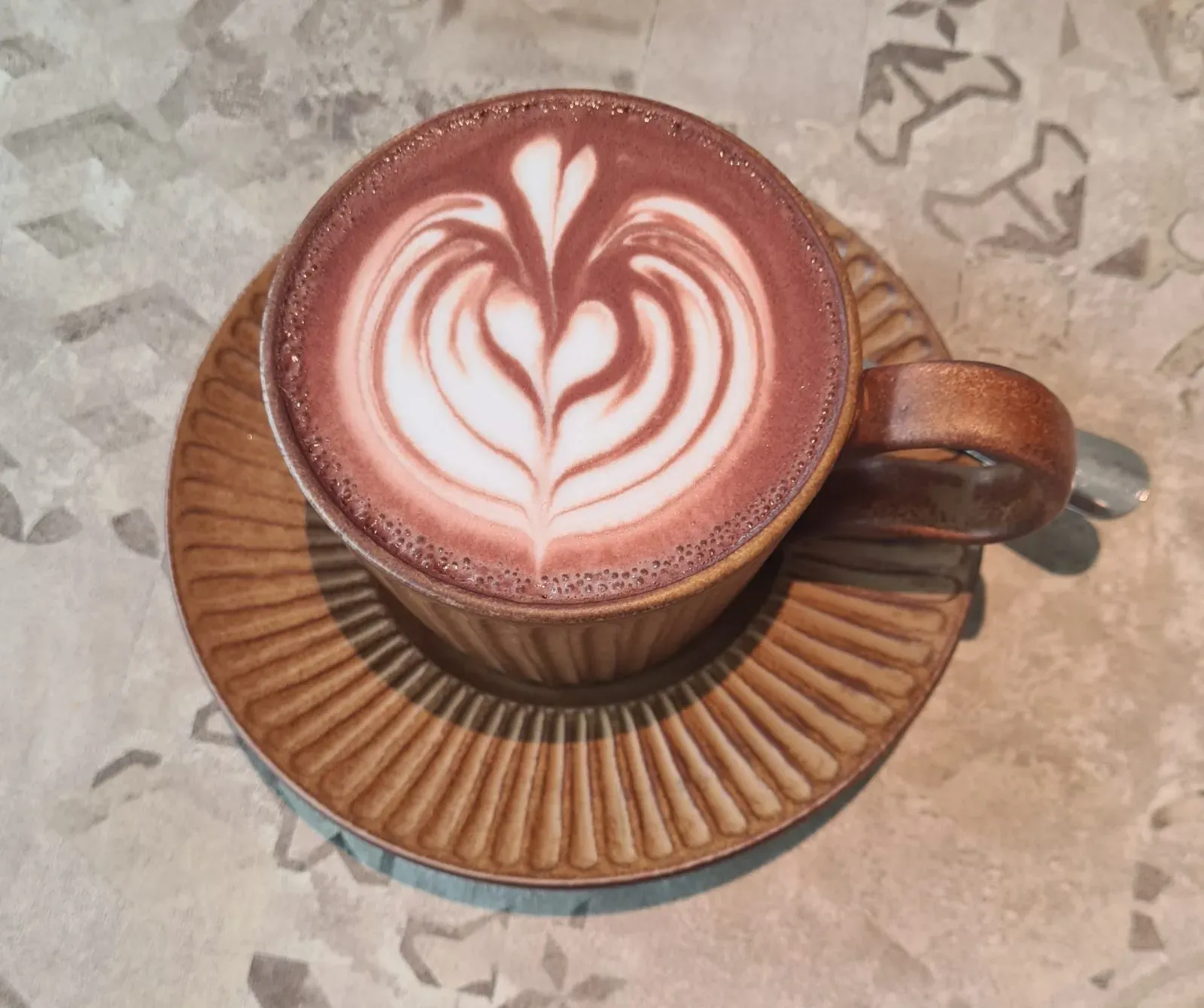 Cawan coklat panas dengan seni latte berbentuk daun